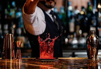 Barman professionnel préparant un cocktail signature avec un éclaboussement dramatique derrière le bar de luxe.