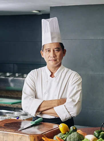 Chef exécutif professionnel se tenant avec assurance dans une cuisine de restaurant moderne.